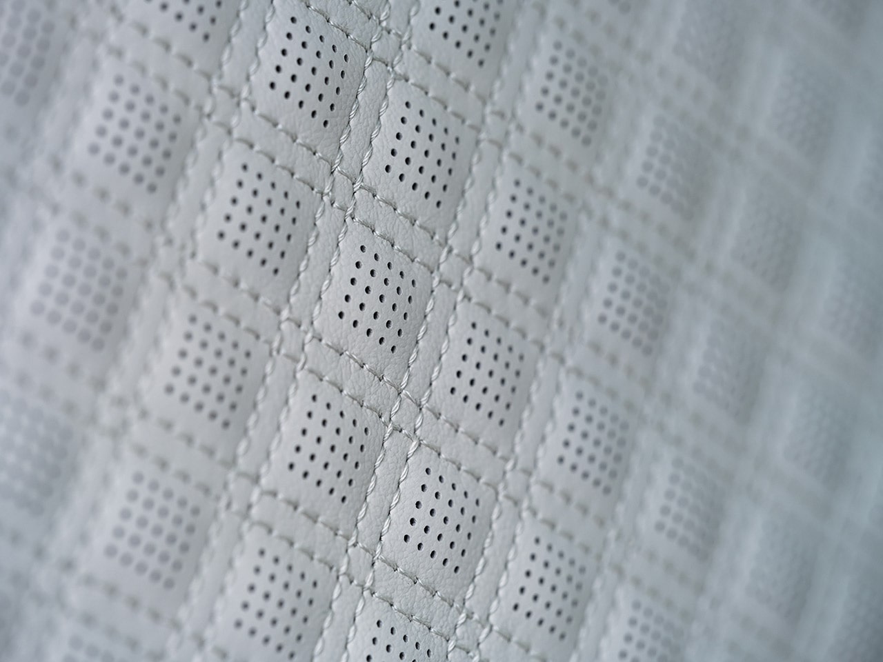 A Close-up View of Light Gray Quilted Perforated Leather Seating with Diamond Stitching