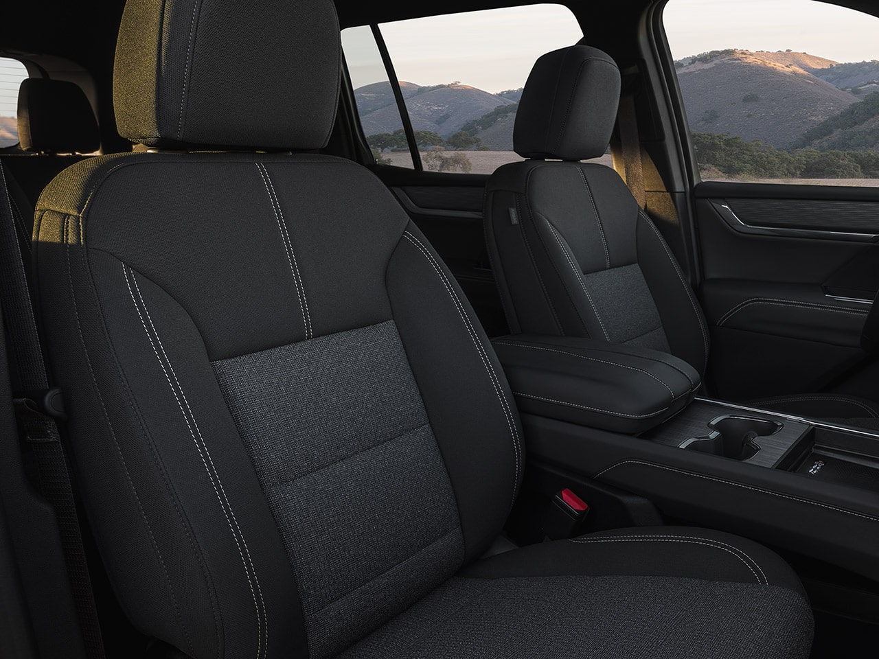 The Interior Front Seats of a GMC Vehicle with Dark Gray Fabric and White Stitching