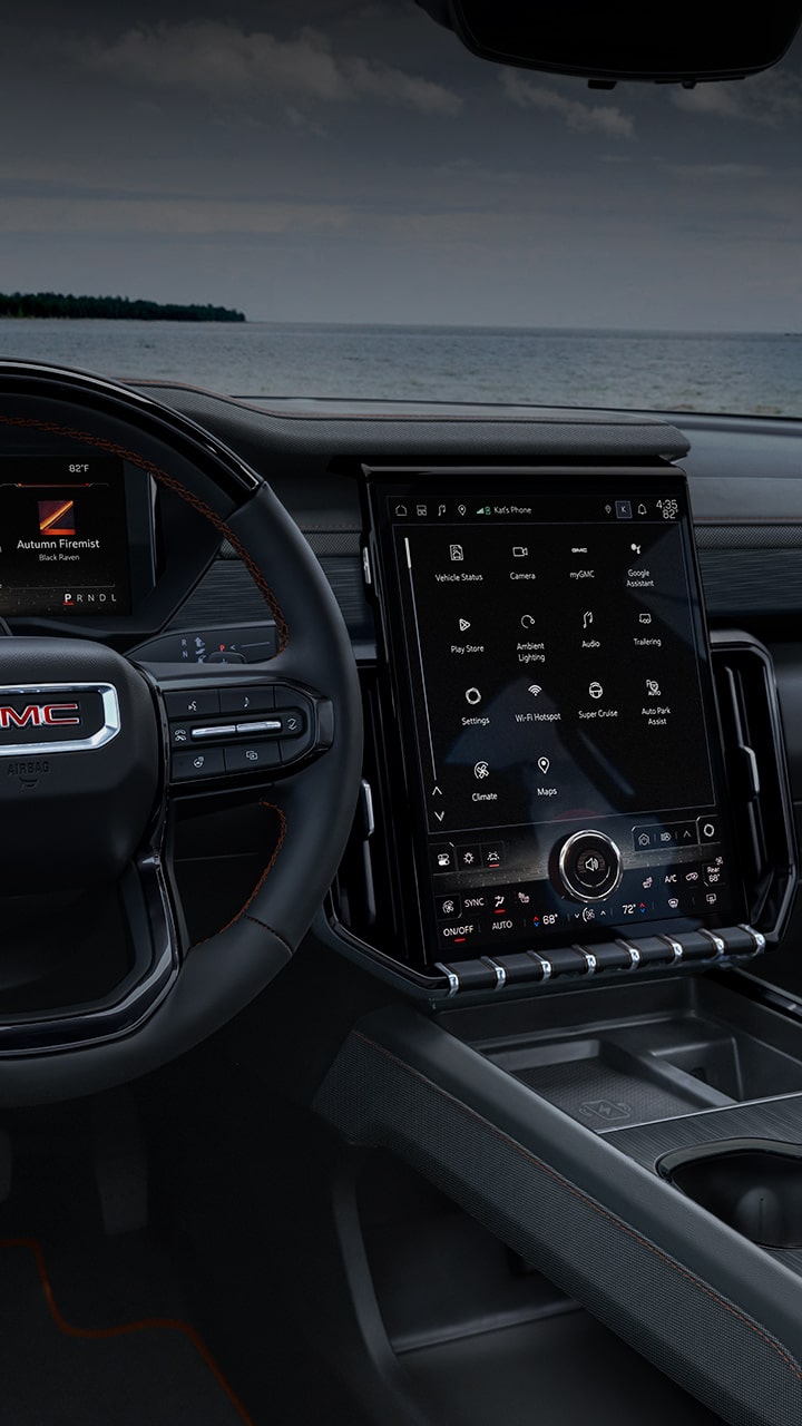 The Interior of a GMC Vehicle, Showcasing The Steering Wheel With The GMC Logo and The Large Integrated Digital Display System