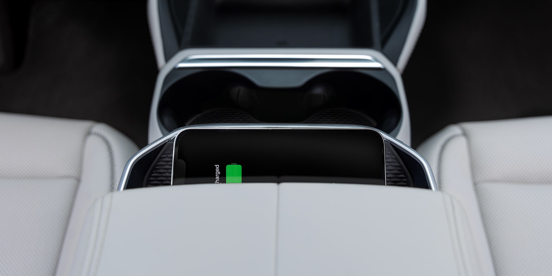 A Smartphone is Wirelessly Charging in the Center Console of a GMC Vehicle with Light Colored Seats