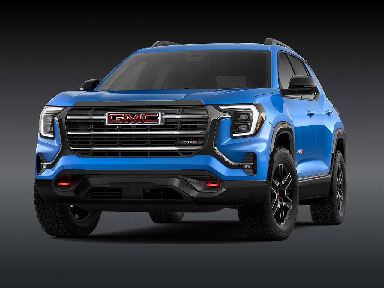A Front Exterior View of a Bright Blue GMC AT4 SUV with a Prominent Grille Headlights and Rugged Tires