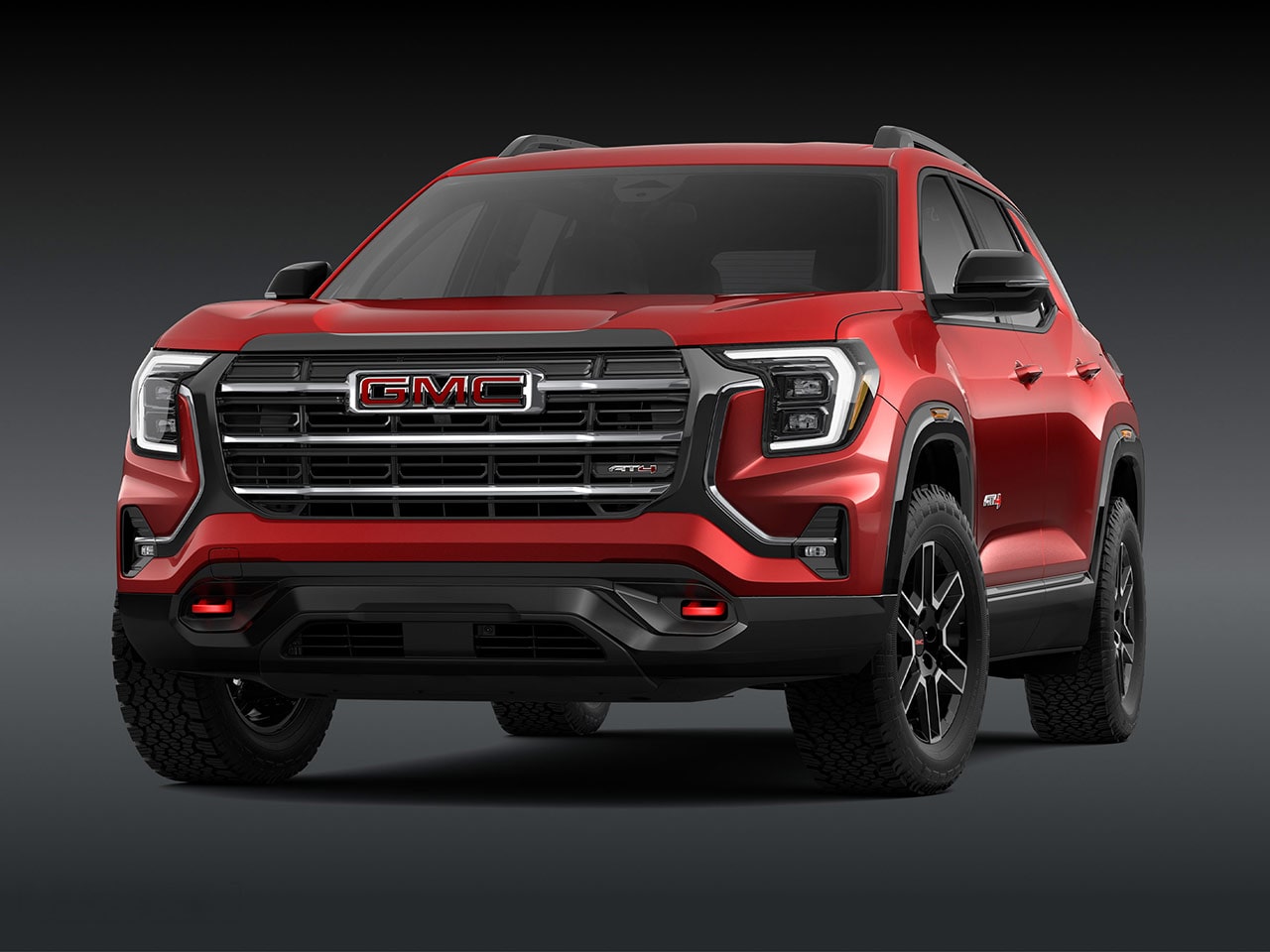 A Front Exterior View of a Bold Red GMC AT4 SUV with a Prominent Grille Headlights and Rugged Tires