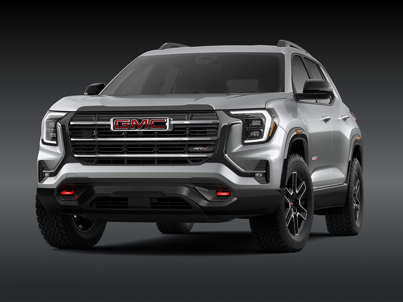 A Front Exterior View of a Sleek Silver GMC AT4 SUV with a Prominent Grille Headlights and Rugged Tires