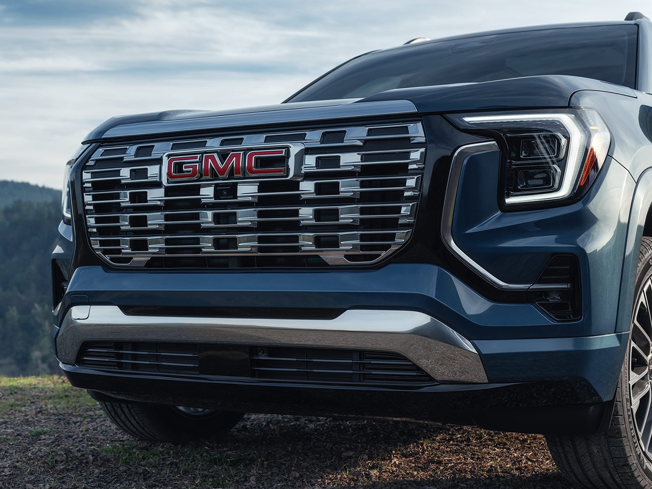 The Front Grille of a Dark Blue GMC SUV Featuring the Red GMC Logo and Bright Led Headlights