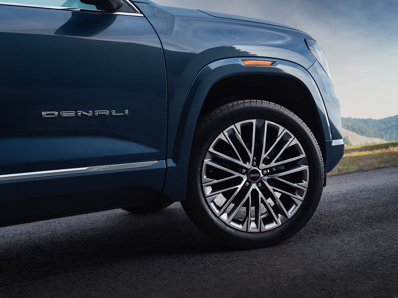 A Close-up of the Wheel and Fender of a Dark Blue GMC Denali SUV with the Denali Badge