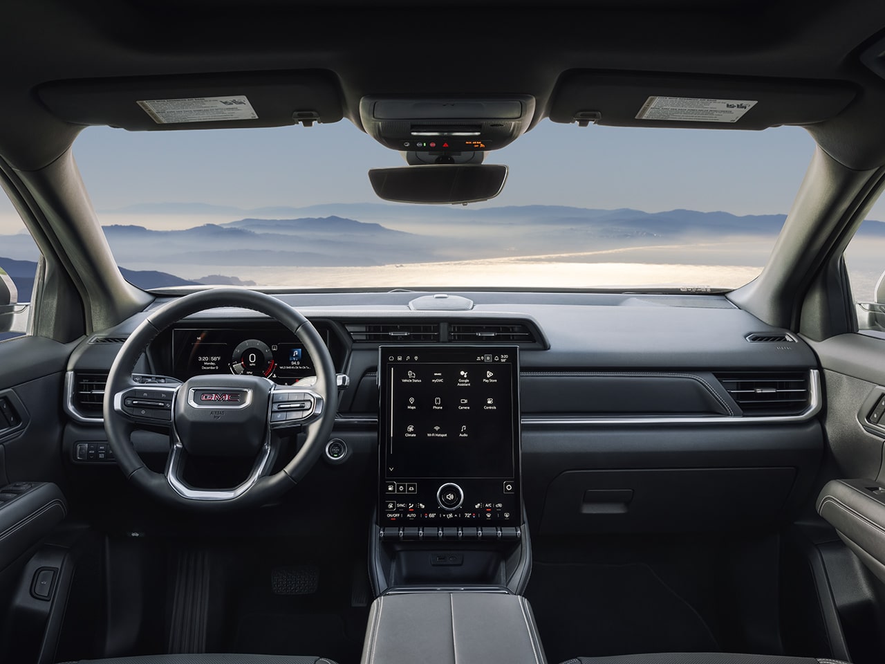 Interior View of a GMC Dashboard with Steering Wheel and Infotainment Screen Overlooking Misty Mountains