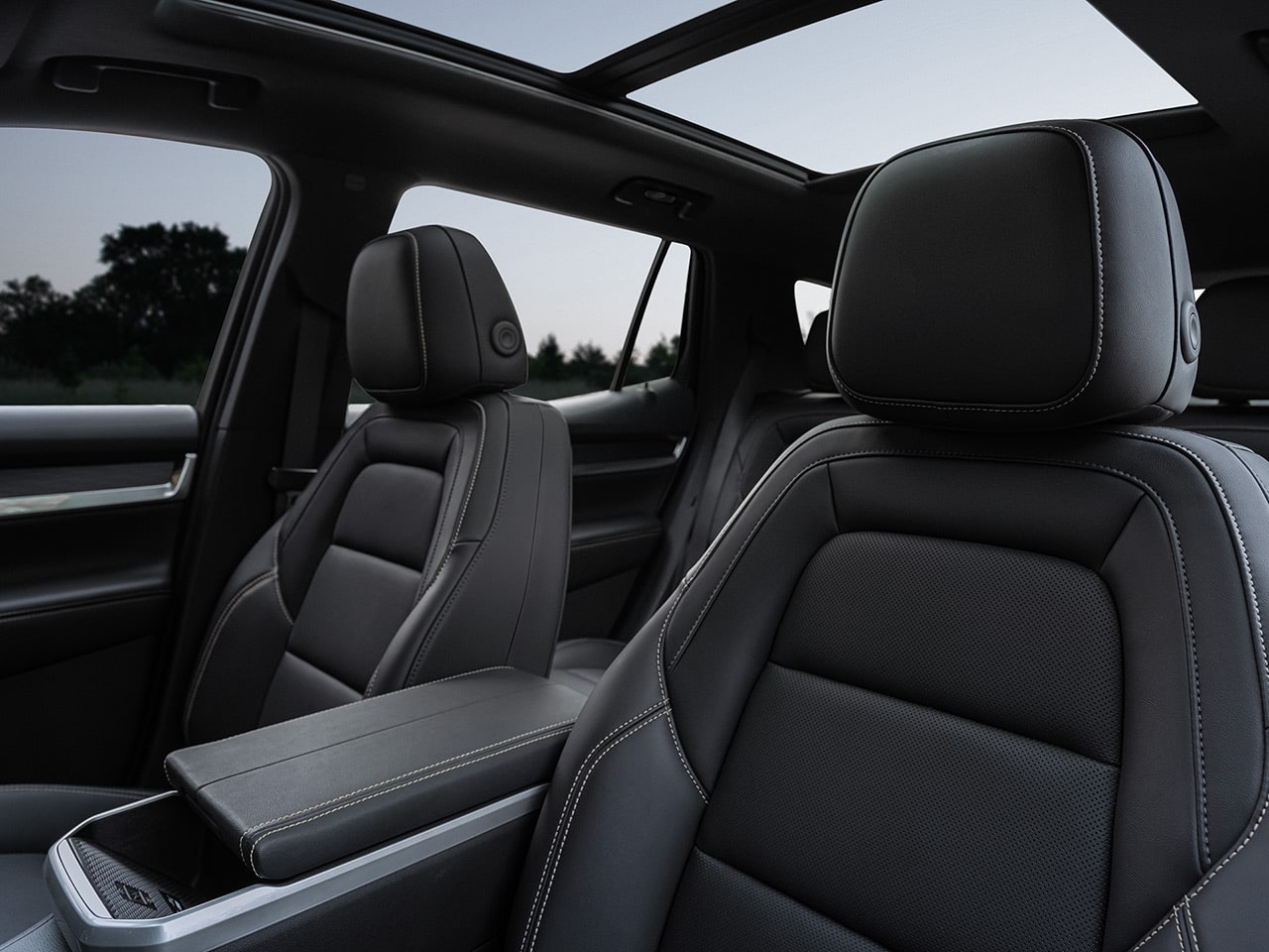 Interior View of a GMC Vehicle's Black Leather Front Passenger Seats with White Stitching and a Panoramic Sunroof