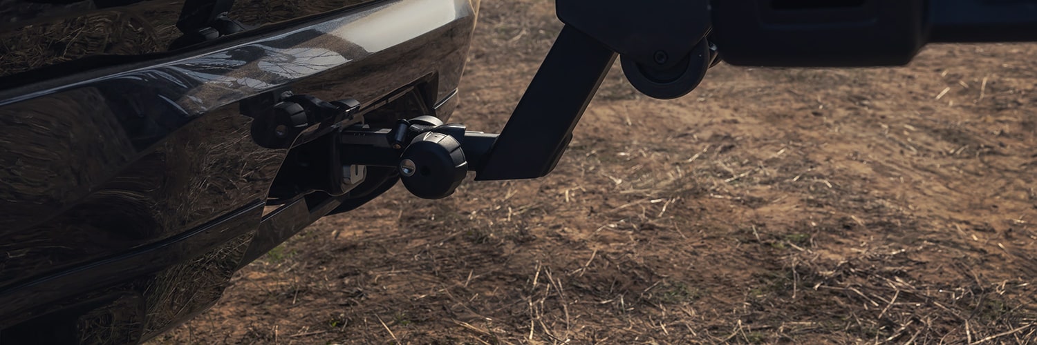 A Close-Up View of the Rear Bumper of a White GMC SUV with a Bike Rack Holding a Bicycle Wheel