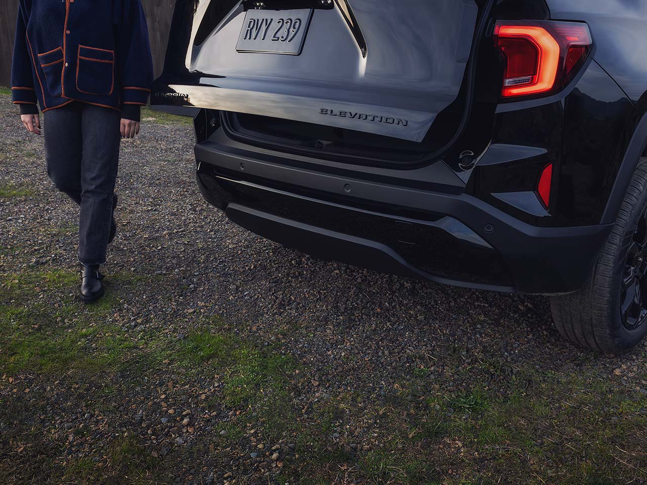A Rear View of a Black GMC Elevation SUV with the Tailgate Open as a Person Approaches it