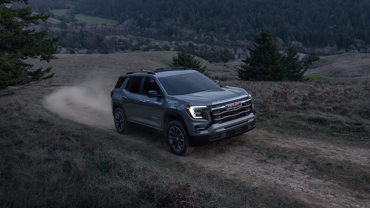 A Gray GMC Denali SUV Kicking Up Dust as it Drives on a Dirt Trail through a Valley