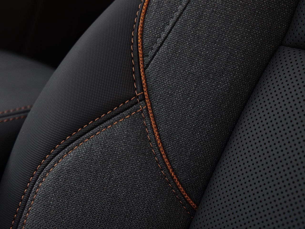 Close-Up of a Dark Gray Car Seat with Textured Fabric, Perforated Leather, and Orange Stitching