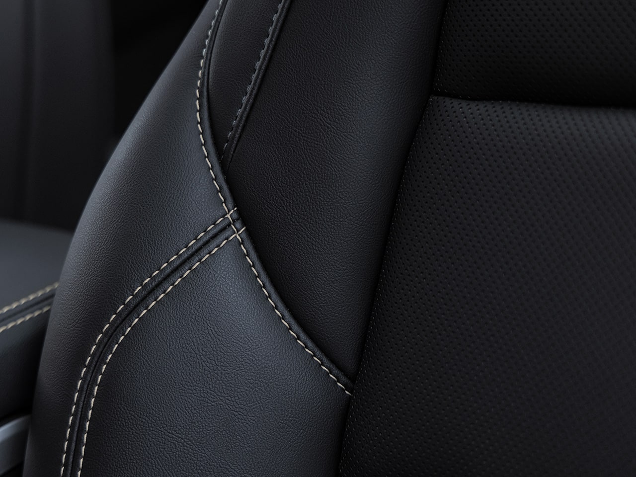 Close-Up of a Dark Gray Perforated Leather Car Seat with Light-Colored Stitching
