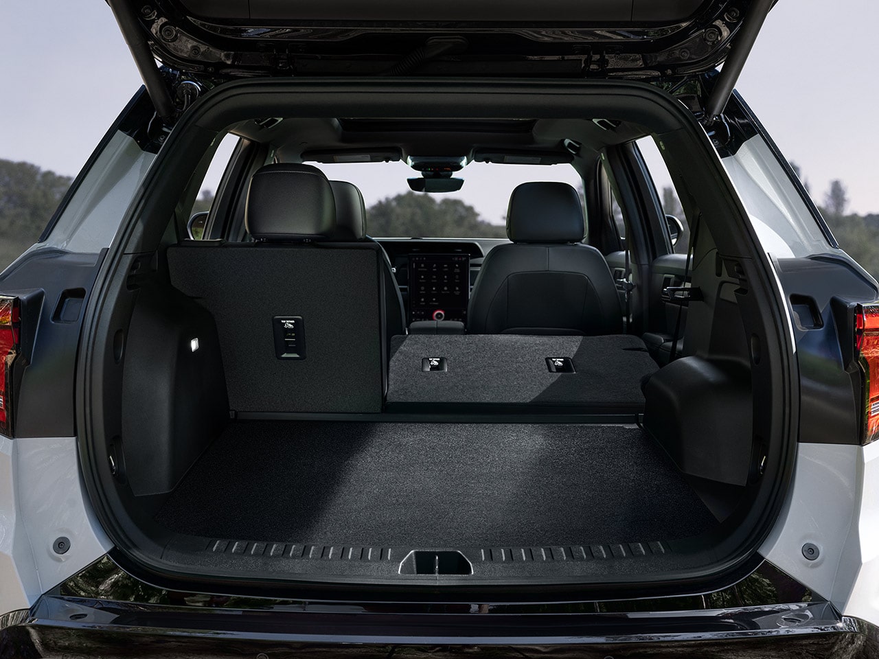 An Open Rear Cargo Area of a White GMC SUV With the Second-Row Seats Folded Flat And Ample Storage Space