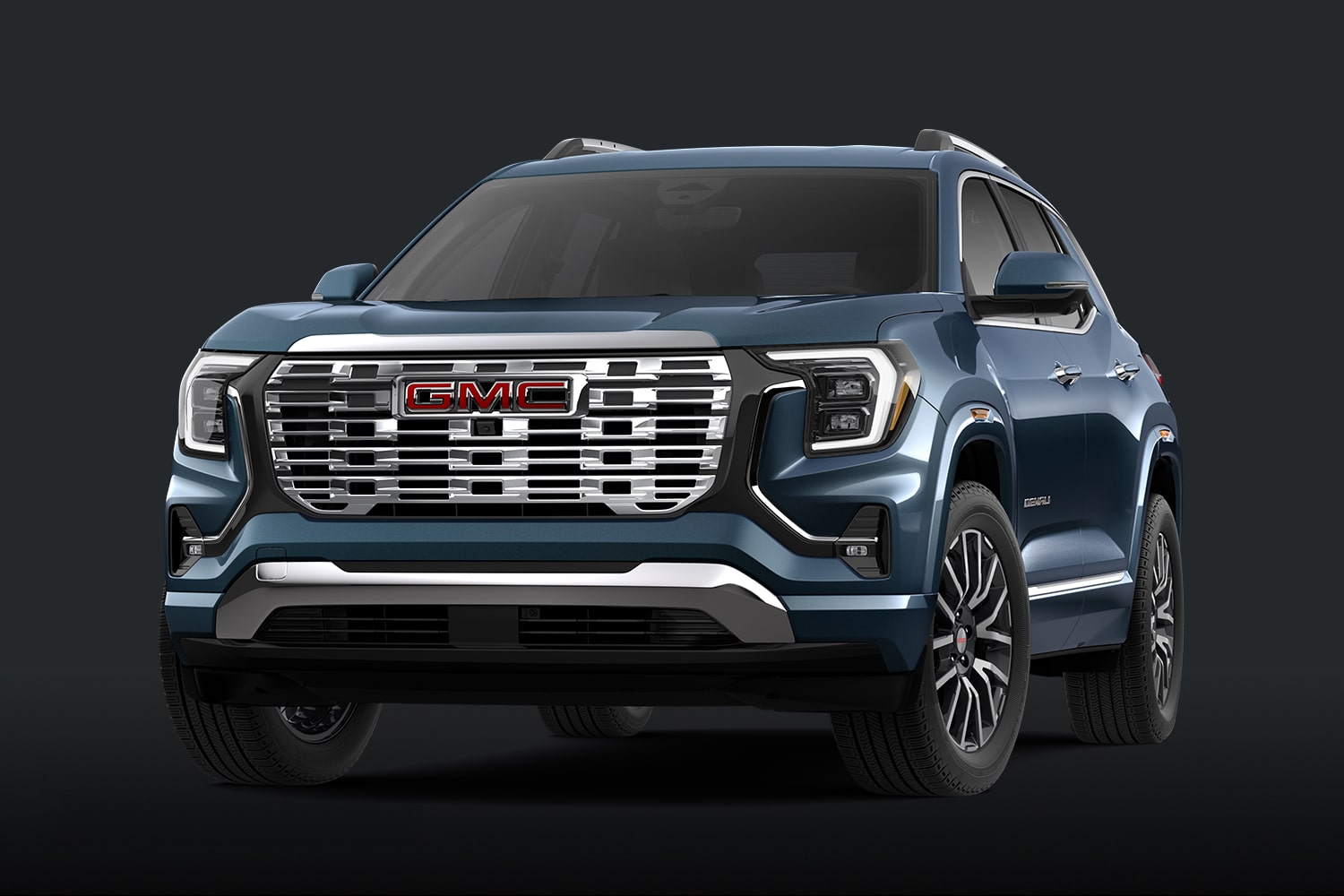 A Teal Blue GMC Denali SUV With a Chrome Grille Against a Dark Background