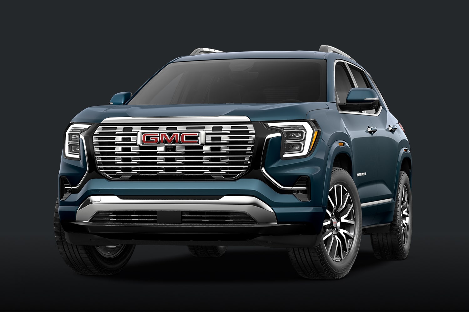 A Teal Blue GMC Denali SUV With a Chrome Grille Against a Dark Background