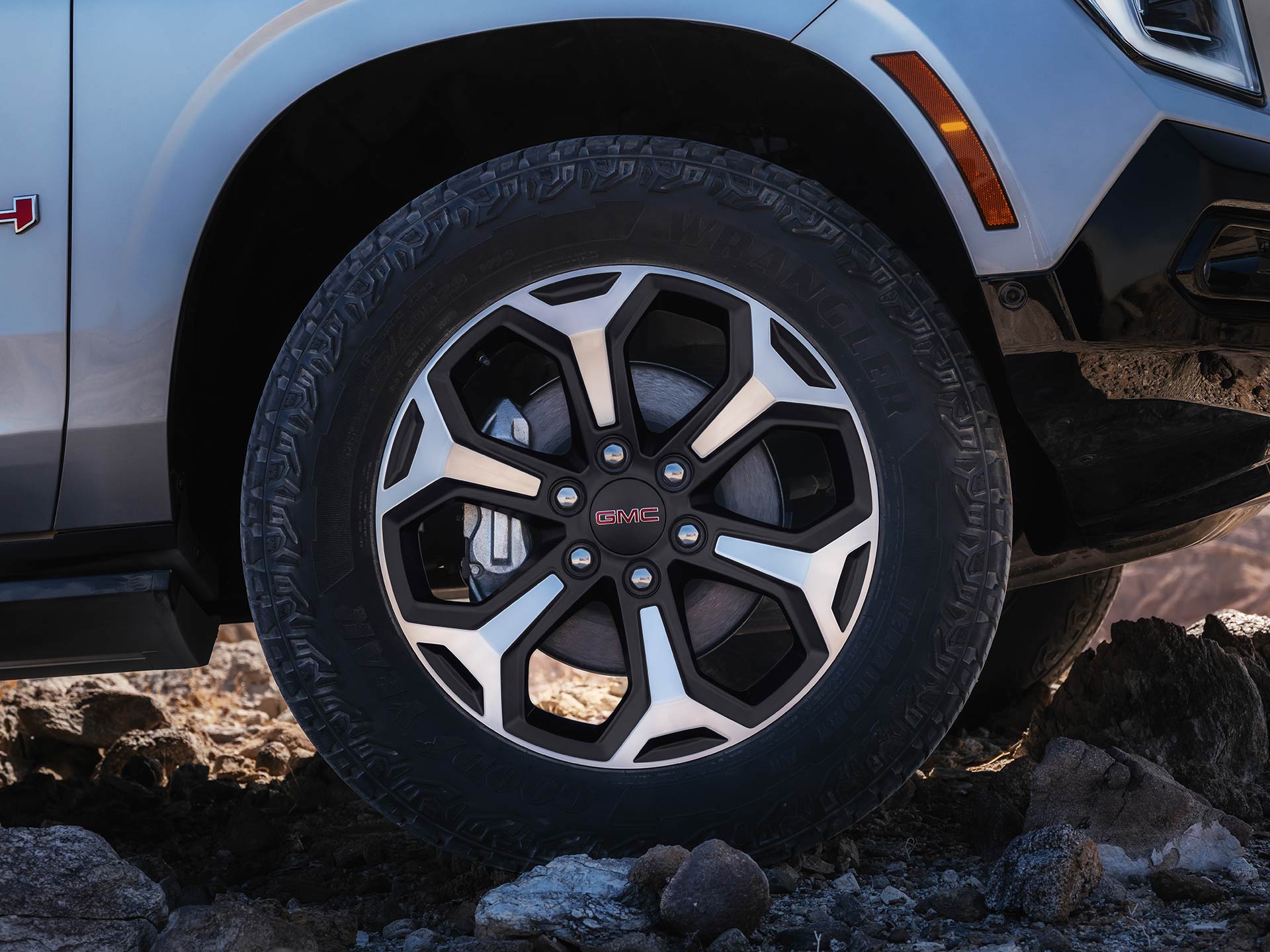 Close-up of the Front Wheel and Fender of a 2027 GMC Yukon AT4 on Rocky Terrain