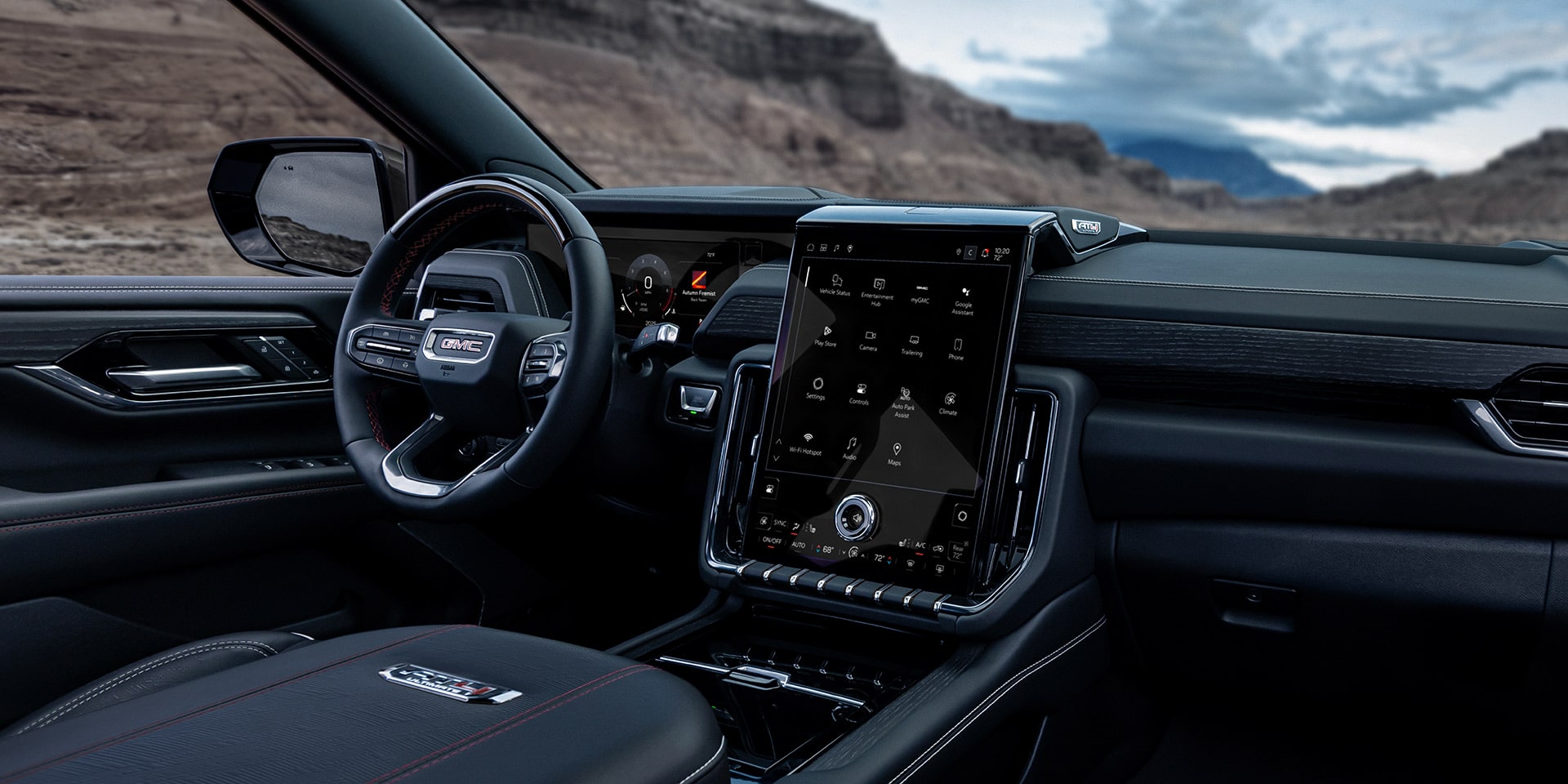 Wide Interior Shot of the 2027 GMC Yukon Dashboard with a Large Touchscreen and Steering Wheel in a Desert Landscape