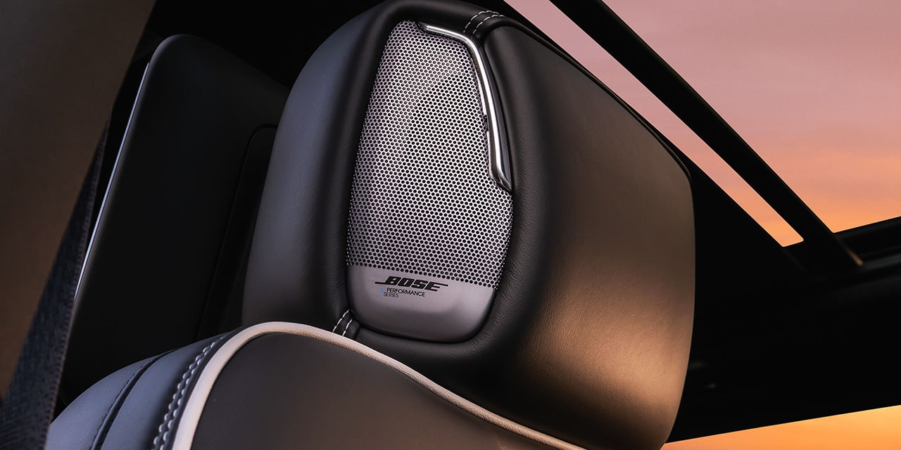 Close-up of a Bose Performance Series Speaker Grille on a Black Leather Seat in the 2027 GMC Yukon