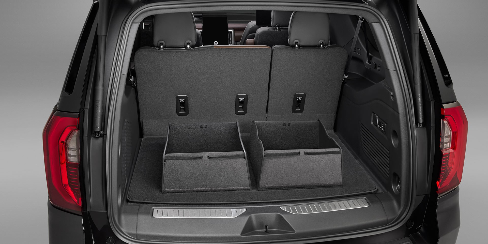 The Rear Cargo Area of a Dark GMC Yukon with Two Black Cargo Management Bins