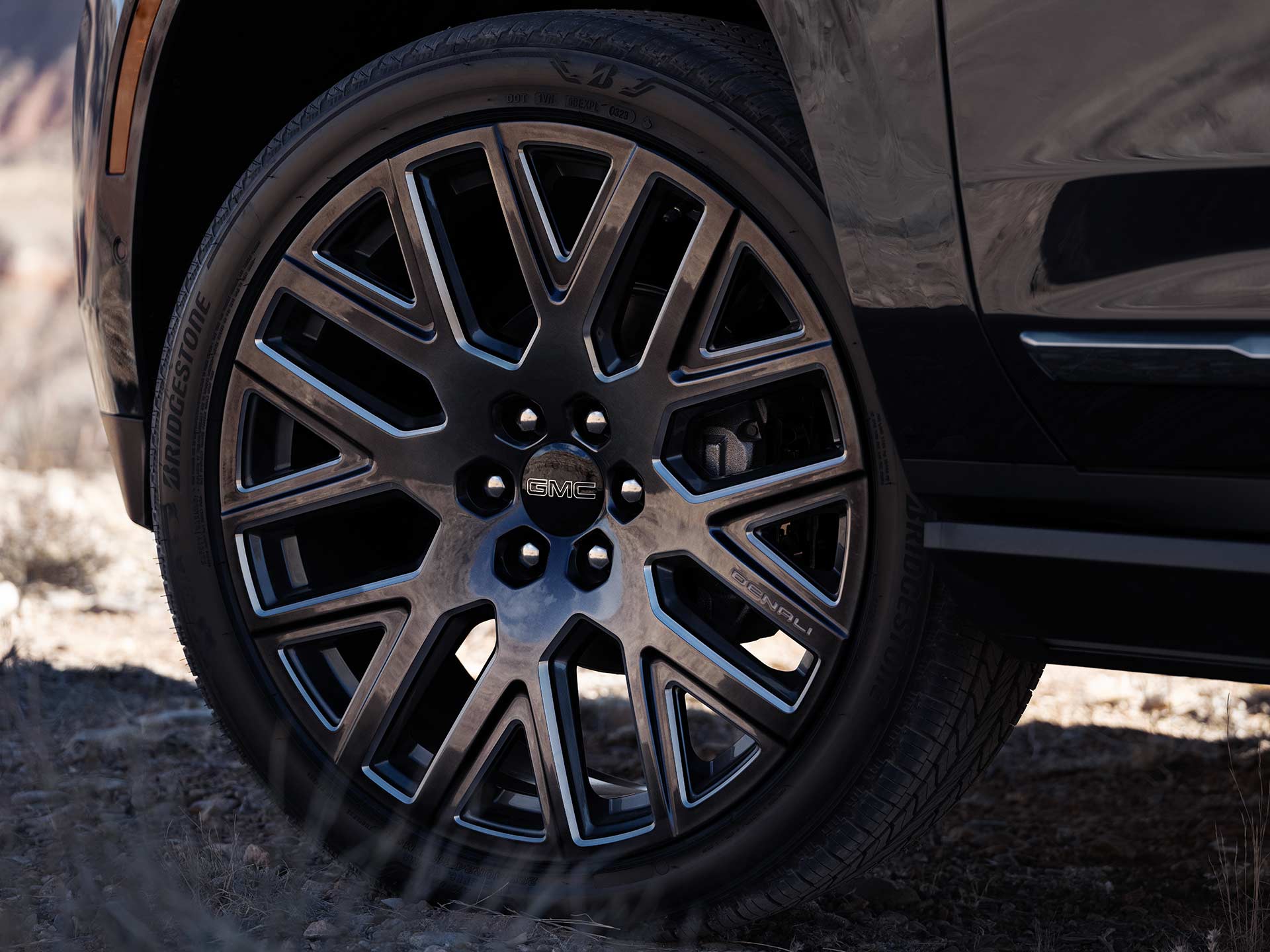 Close-Up of a Dark 2027 GMC Yukon's Black Multi-Spoke Wheel with a GMC Branded Center Cap