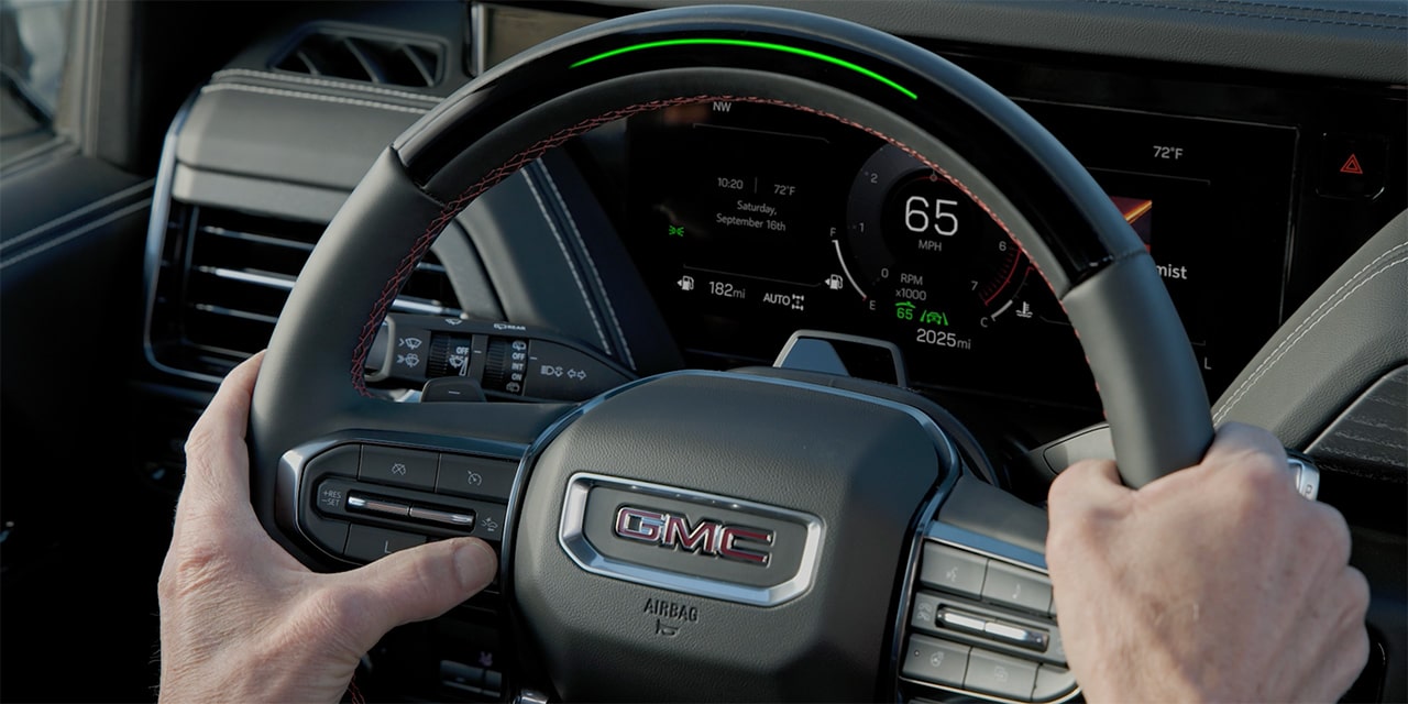 Close-up of the Driver Holding the Steering Wheel as They Press the Super Cruise Control Button on Their Steering Wheel