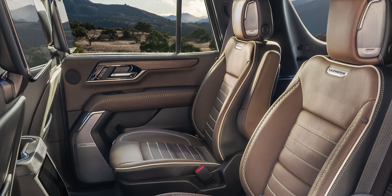 Rear Interior of a 2027 GMC Yukon Denali Ultimate with Brown Leather Seats and the Ultimate Emblem Visible