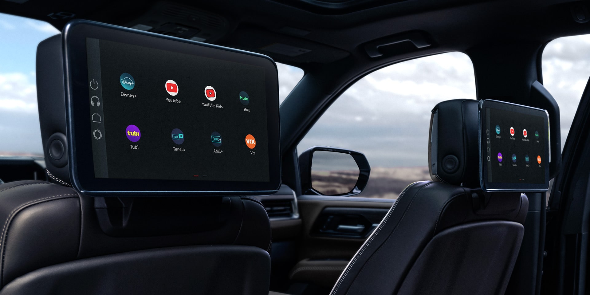 Rear Interior View of a GMC Yukon XL with Dual Seatback Media Screens Displaying Entertainment Options