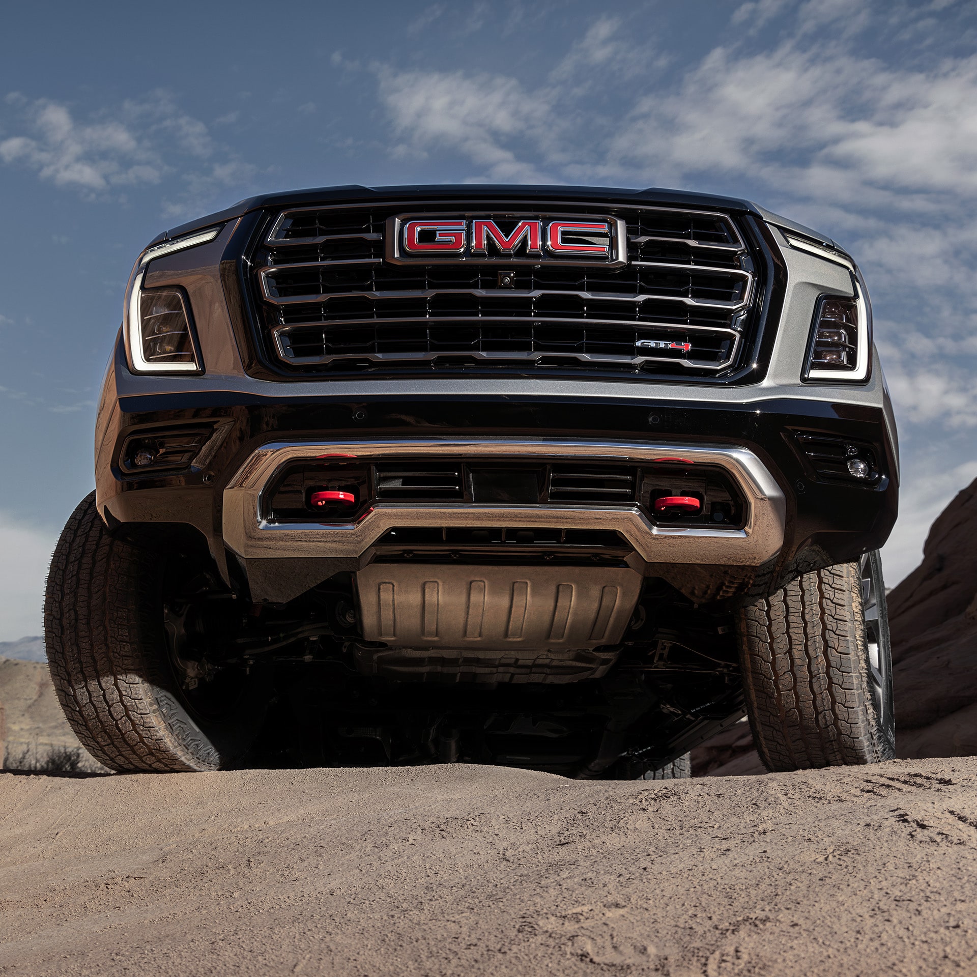An Extreme Low-Angle View of a GMC Yukon AT4 with its Undercarriage and Red Recovery Hooks
