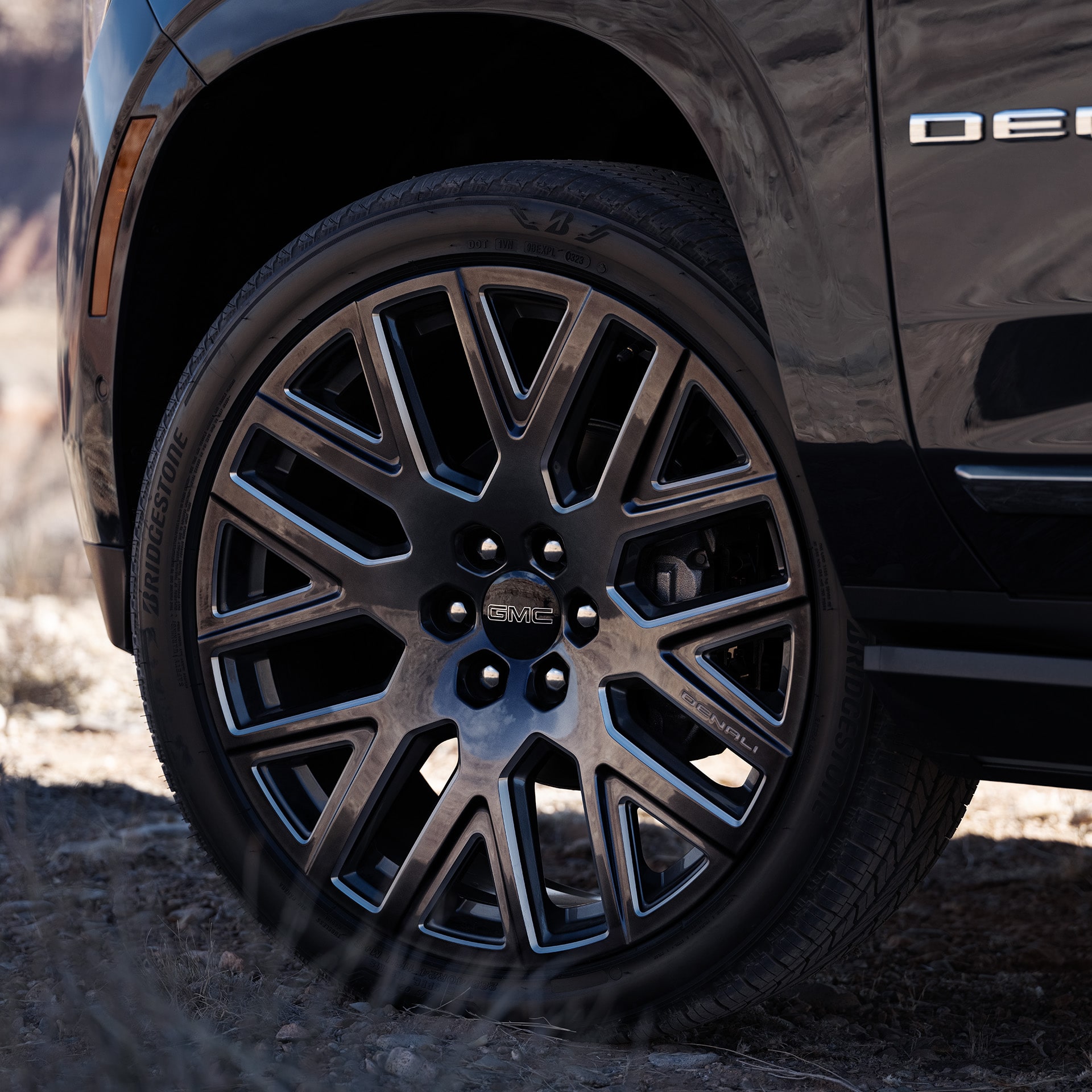 Close-up of a Black Multi-Spoke Wheel on a 2027 GMC Yukon Denali with a Denali Badge