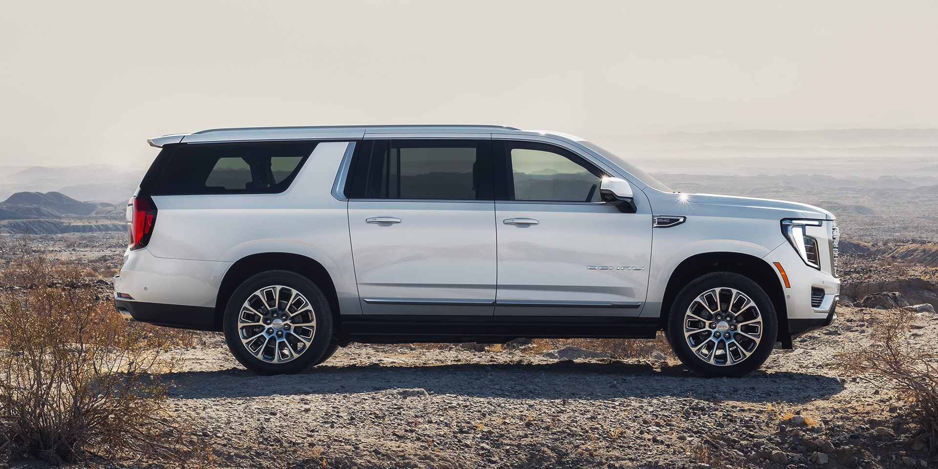 Side Profile of a White 2027 GMC Yukon XL Denali Parked on a Dirt Road