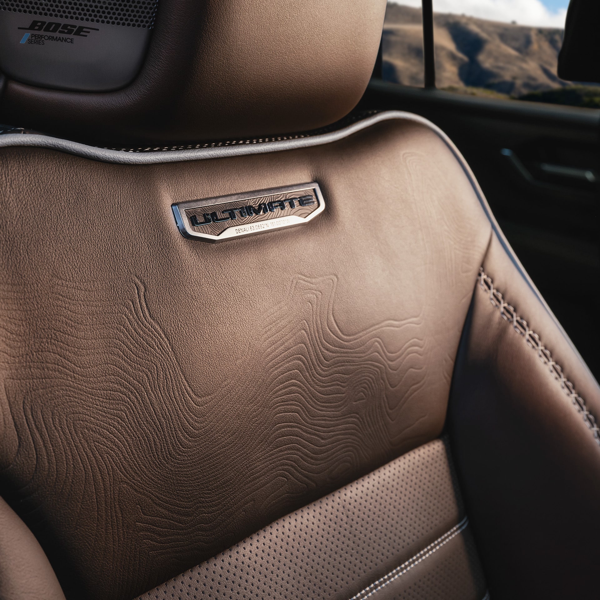 Close-up of a Brown Leather Seat with an Ultimate Emblem and Topographic Pattern in a 2027 GMC Yukon Denali Ultimate