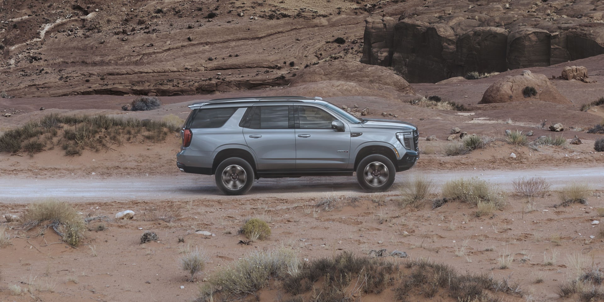 A Gray GMC Yukon AT4 Driving on a Dirt Road in a Desert Landscape