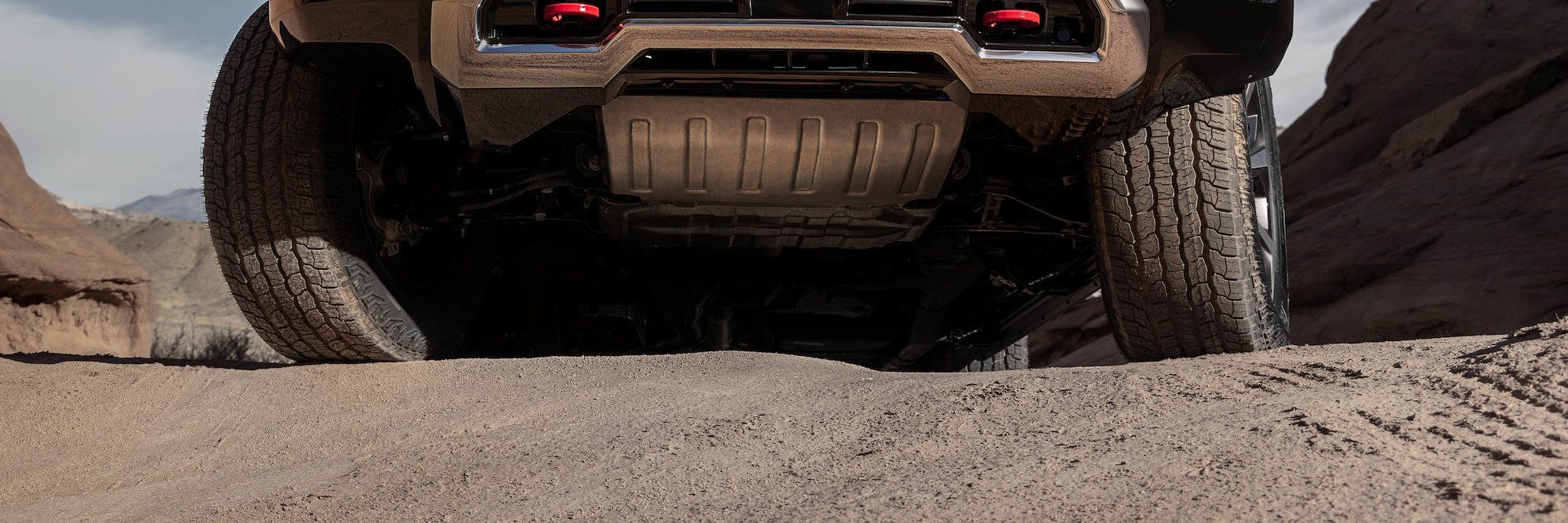 An Extreme Low-Angle View of a GMC Yukon AT4 with its Undercarriage and Red Recovery Hooks