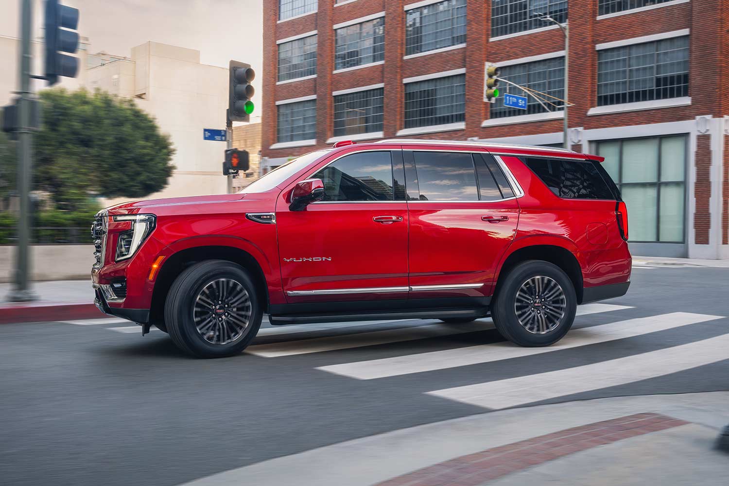 A Red GMC Yukon Driving on a City Street with Buildings and Traffic Lights