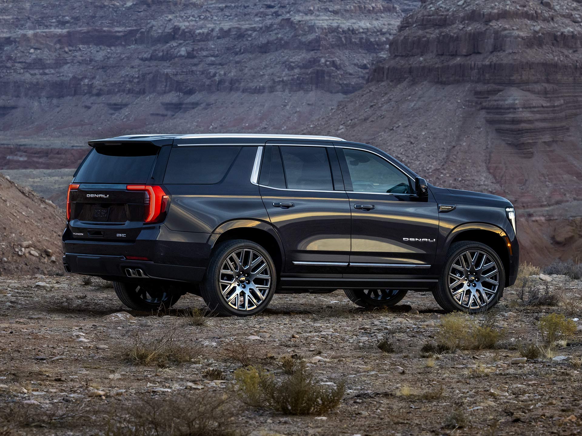A Dark GMC Yukon Denali Parked on Rough Terrain in a Desert Landscape