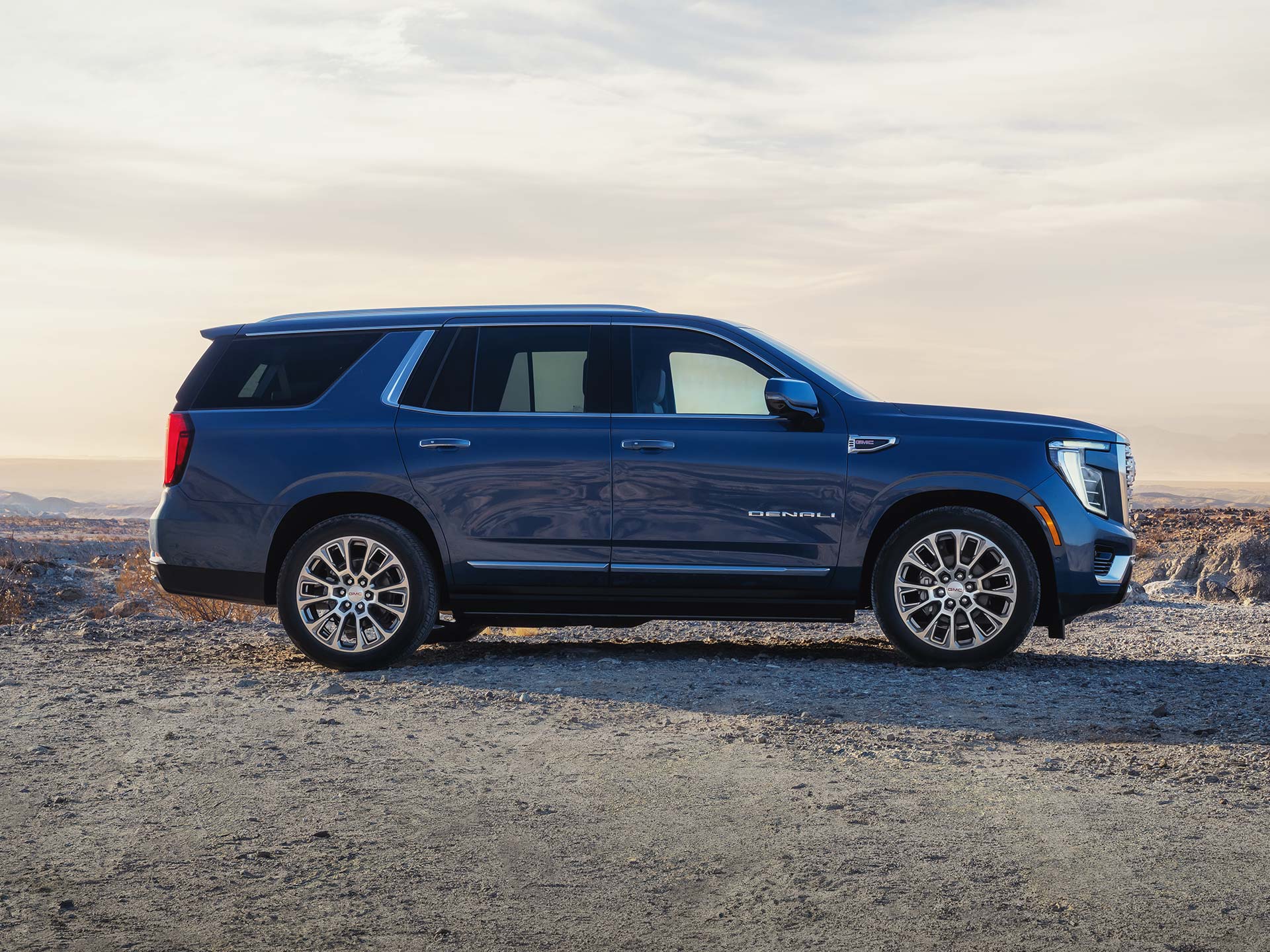 A Blue GMC Yukon Denali Parked on Dry Terrain with Mountains in the Distance