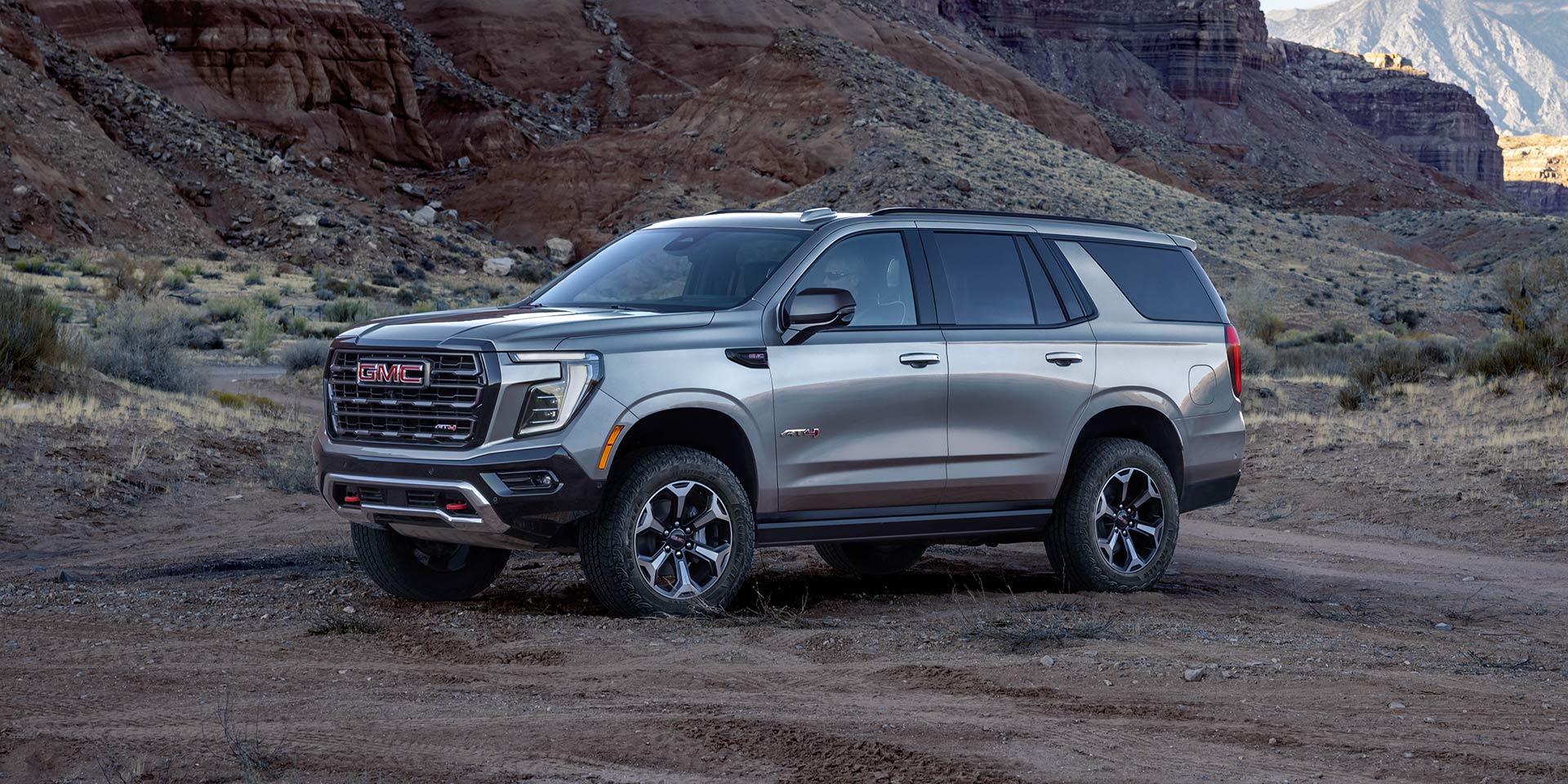 A Gray GMC Yukon AT4 Parked on a Dirt Trail in a Rugged Desert Landscape