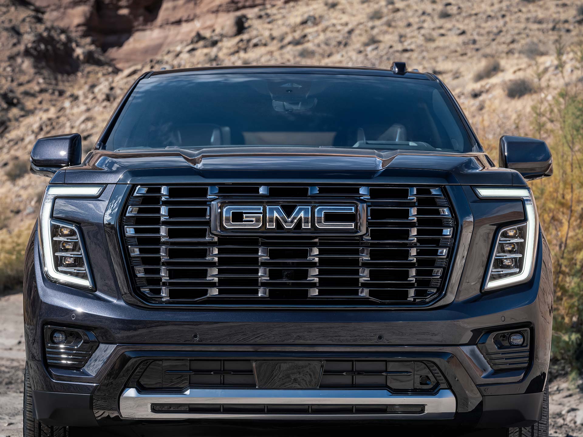 A Close-Up Front View of a Dark Blue GMC Yukon Grille with Chrome Accents