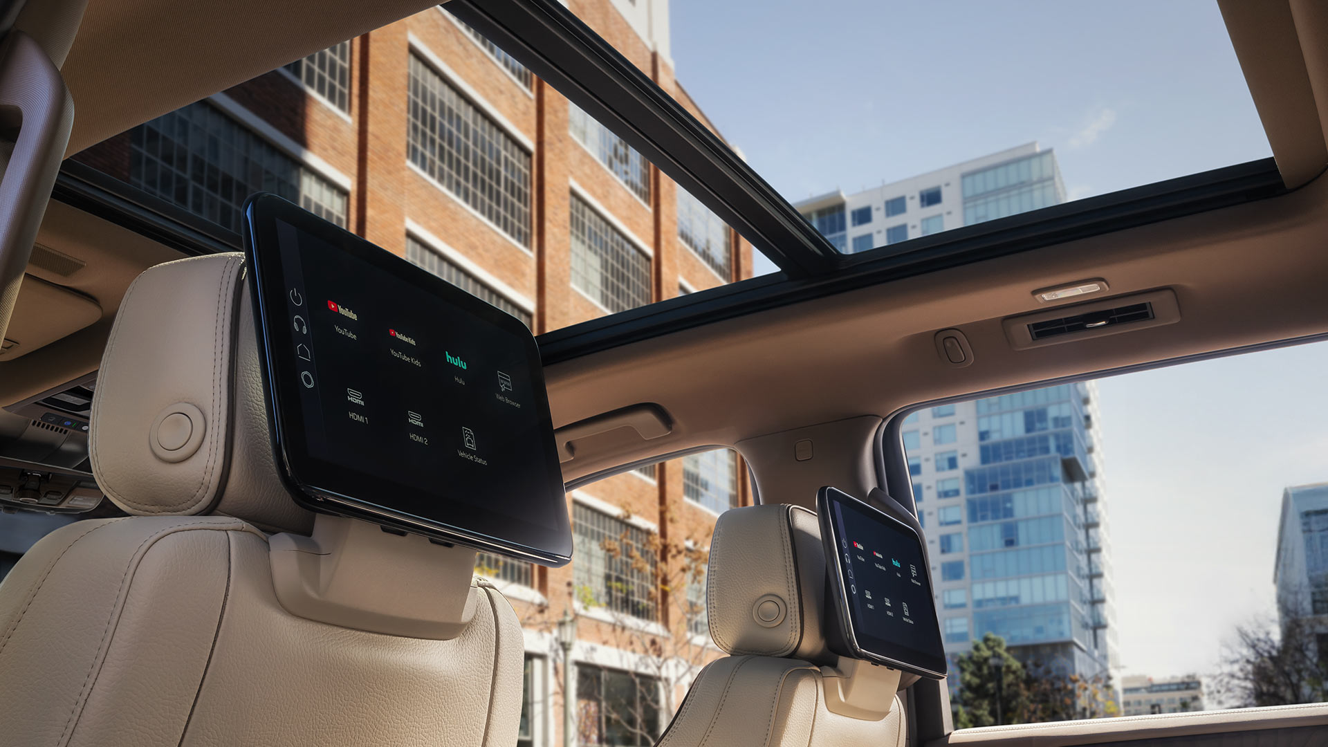 Rear Interior View of a GMC Yukon XL with Dual Seatback Screens and a Panoramic Sunroof in a City Setting