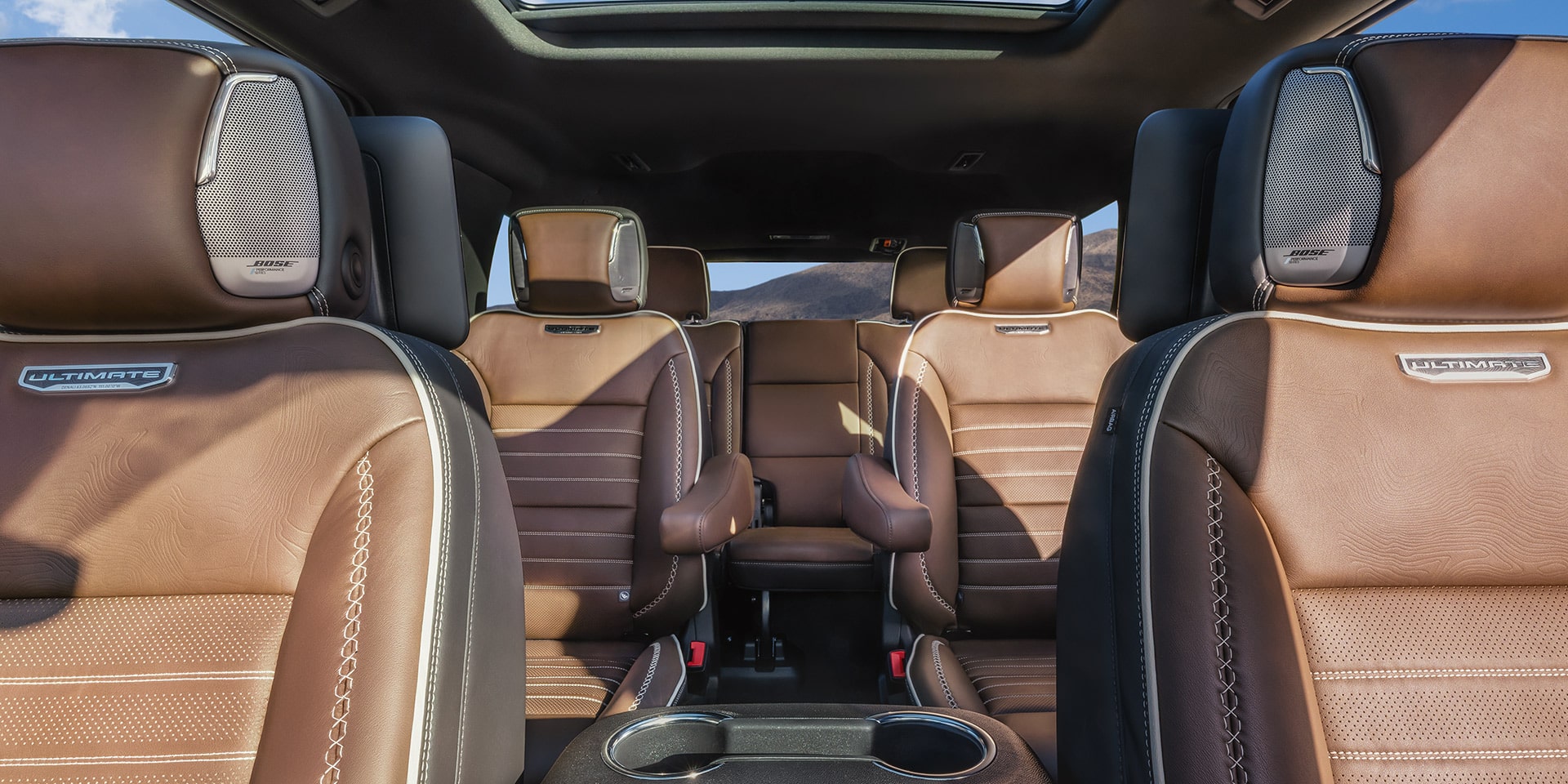 Second Row Interior of a GMC Yukon Denali Ultimate with Brown Leather Captain's Chairs and Integrated Headrest Speakers