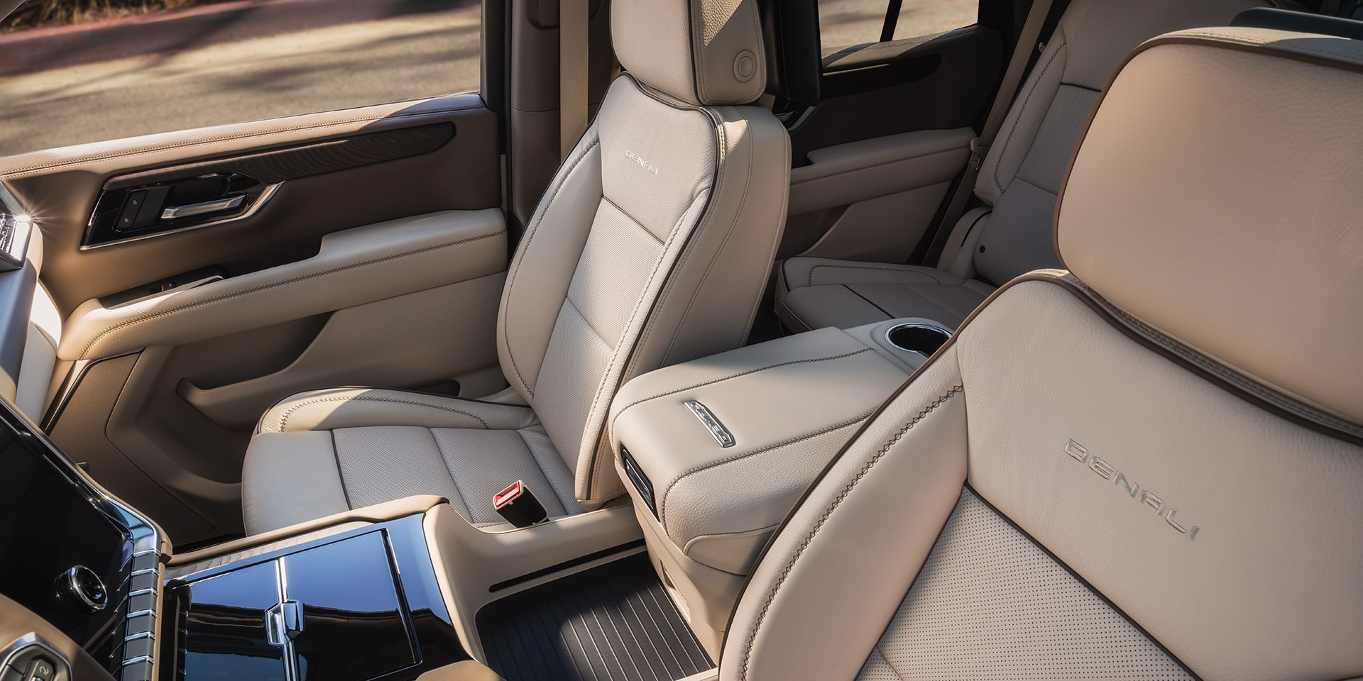 Front and Second Row Interior of a GMC Yukon Denali with Light Beige Perforated Leather Seats and Center Console