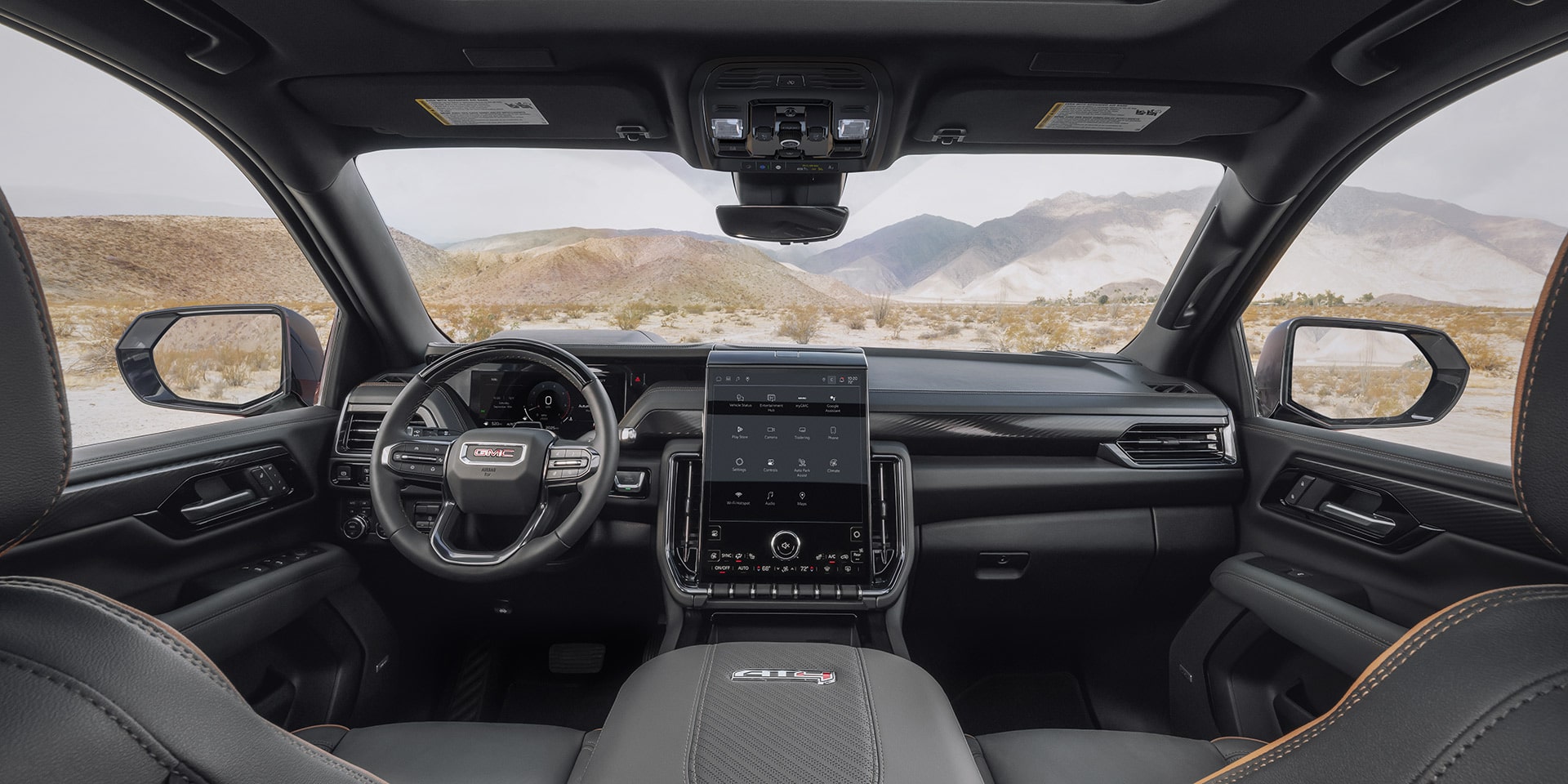 Wide Interior View from the Driver's Seat of a GMC Yukon AT4 with a Large Infotainment Screen and Mountain Backdrop