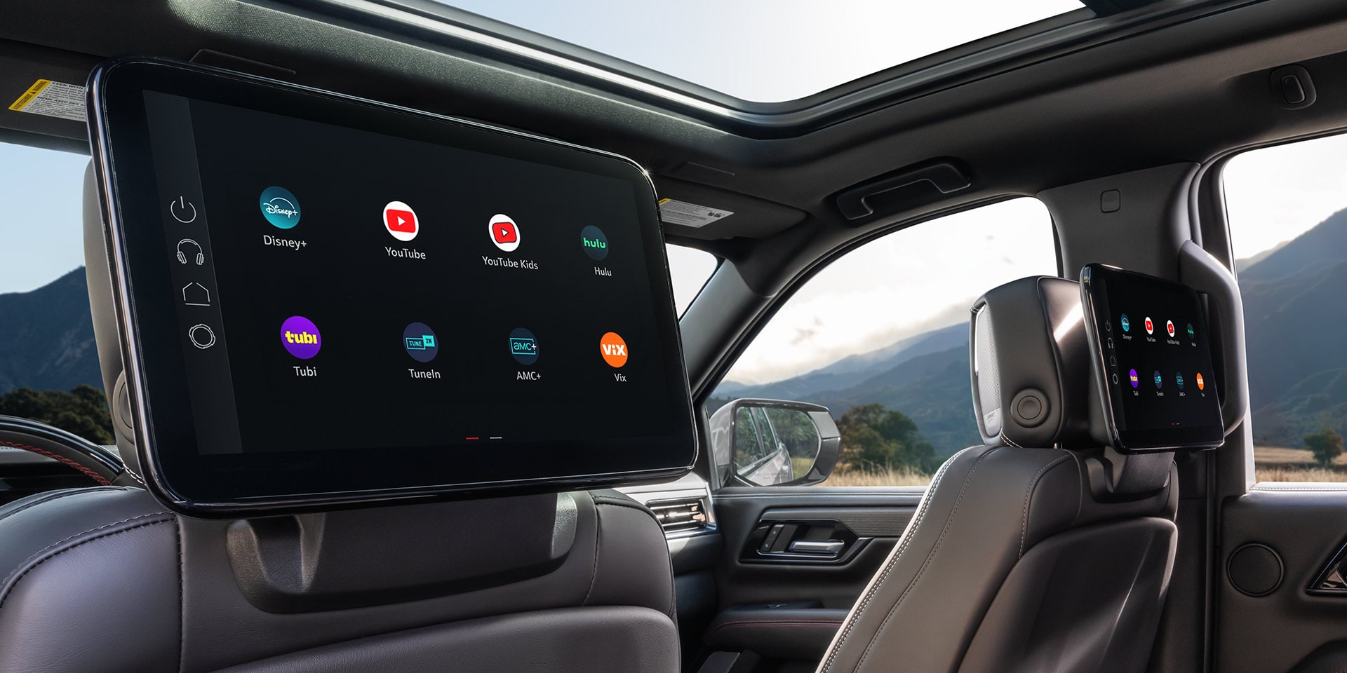 Rear Interior View of a GMC Yukon XL with Dual Seatback Media Screens Displaying Entertainment Options