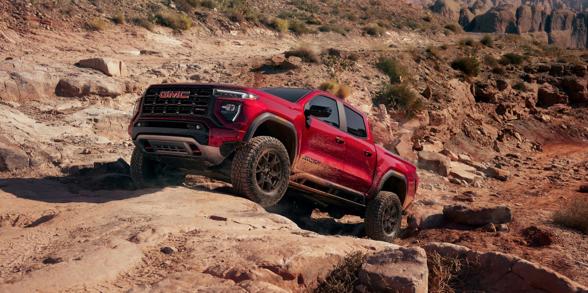 A White 2027 GMC Canyon AT4X Pickup Truck Driving on a Dusty Off-Road Trail