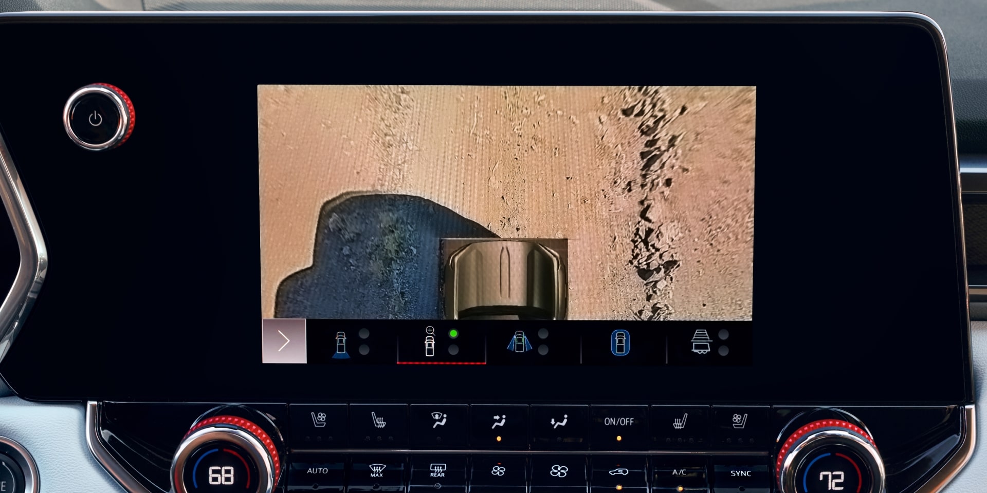 The Interior Dashboard of a 2027 GMC Canyon with an Infotainment Screen Showing a Close-Up Camera View of the Ground and Tire