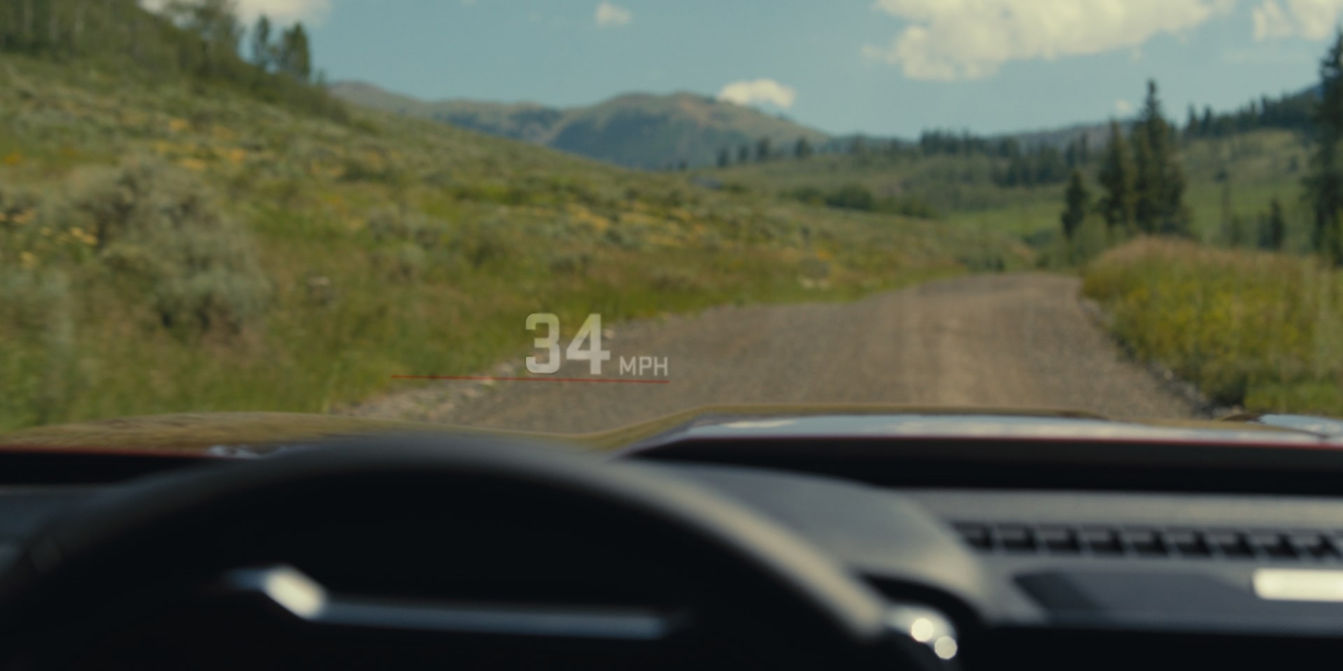 Driver's Perspective From Inside the 2027 GMC Canyon Showing a Heads-Up Display With "34 MPH" on a Dirt Road