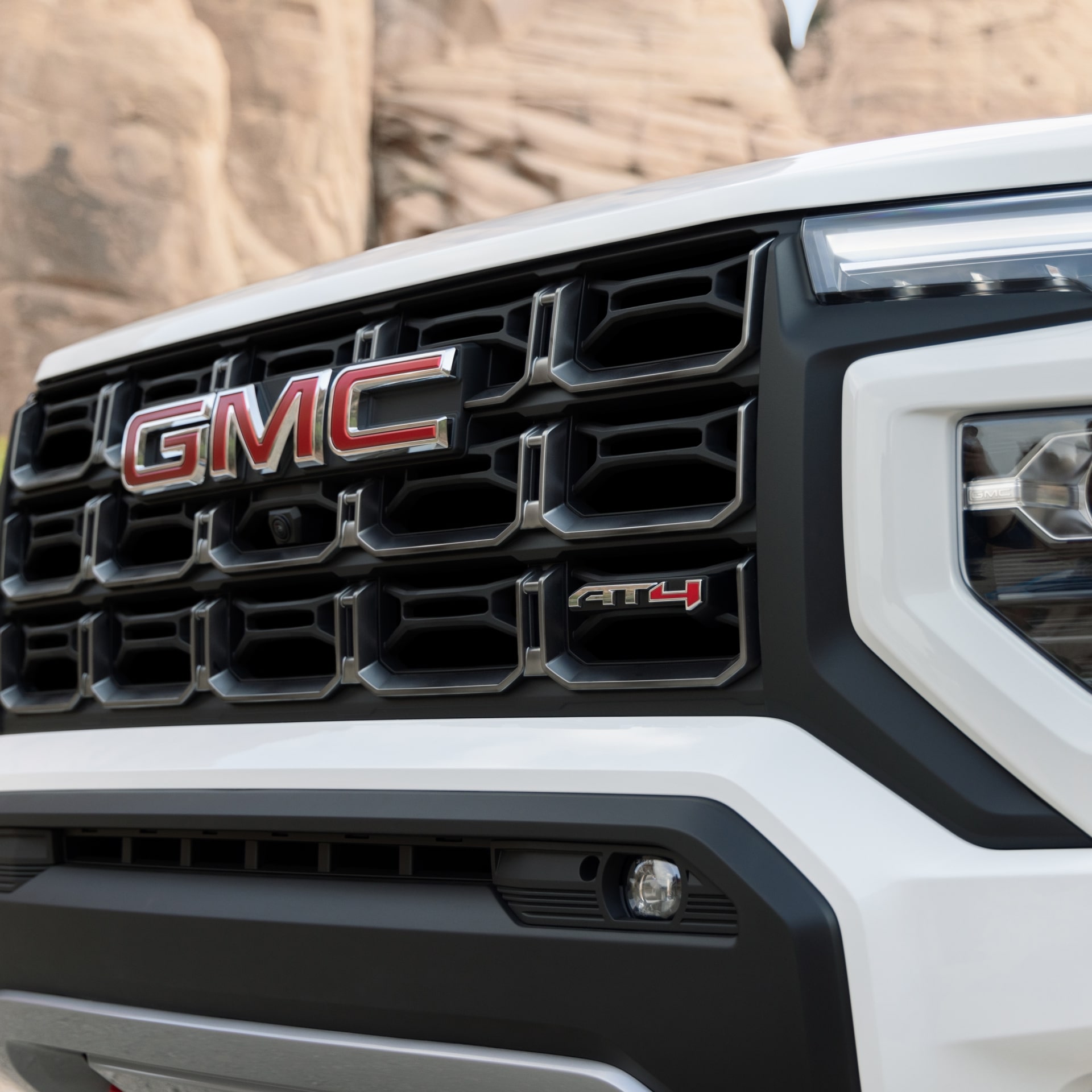 Close-Up Of the Front Grille Of a White 2027 GMC Canyon AT4X Truck With the GMC Logo and AT4X Badge