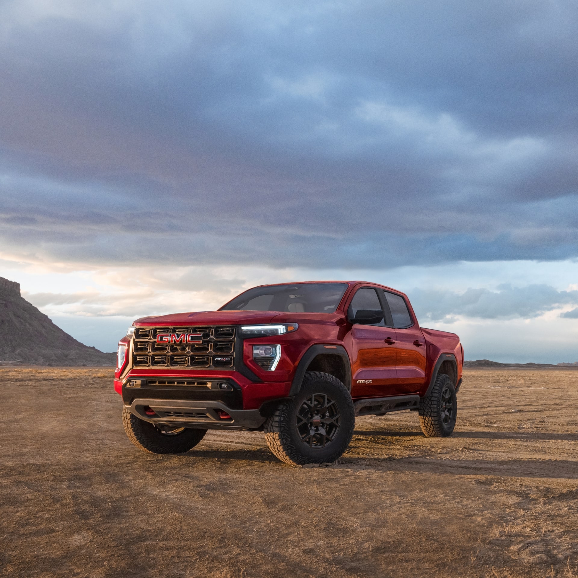 A Red 2027 GMC Canyon AT4X Truck Parked on a Dirt Road in a Desert Landscape