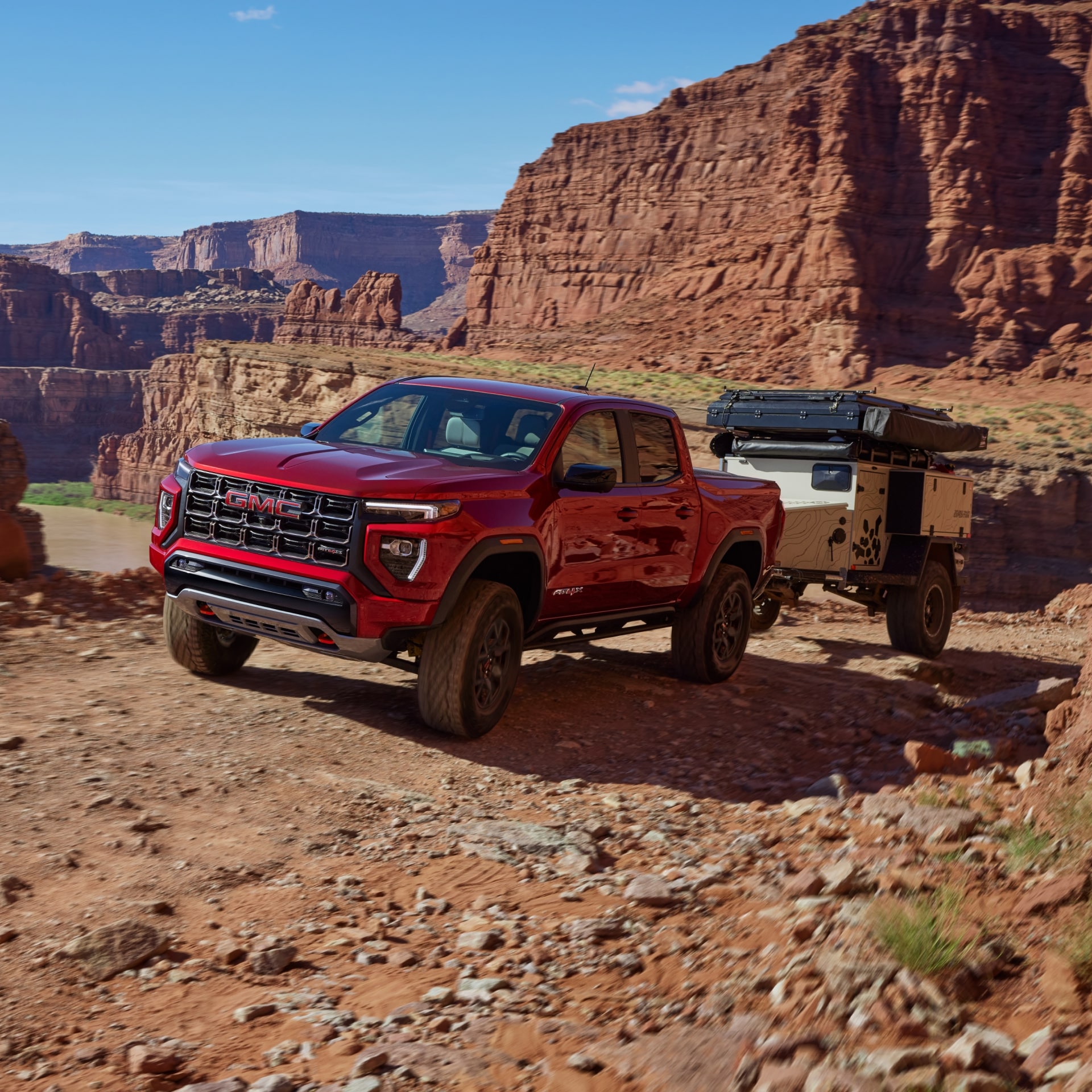 A Red GMC Canyon Pickup Driving Off-Road in a Desert Landscape Towing Cargo