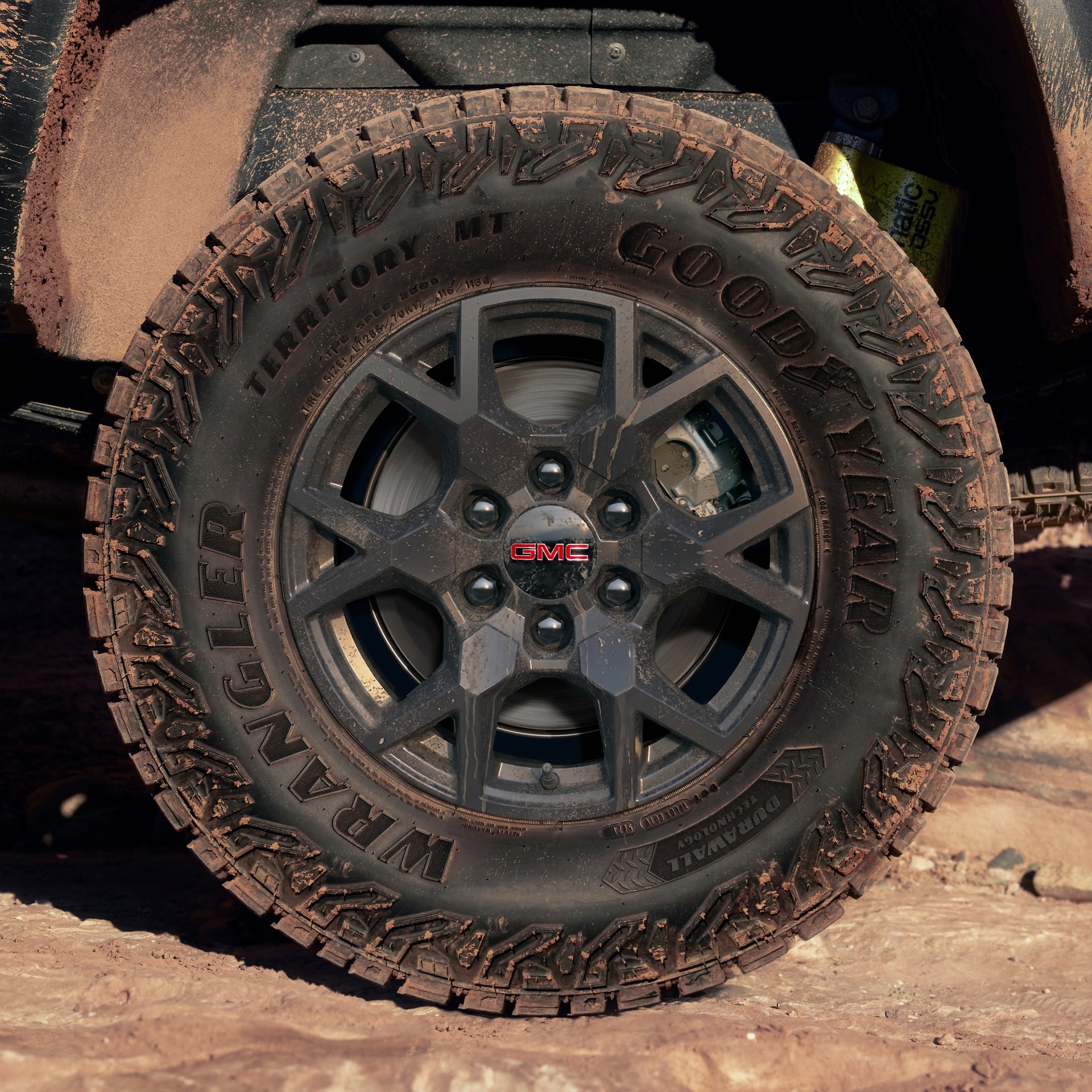 A Close-Up View of a Dirty Goodyear Wrangler Off-Road Tire on a Red 2027 GMC Canyon AT4X
